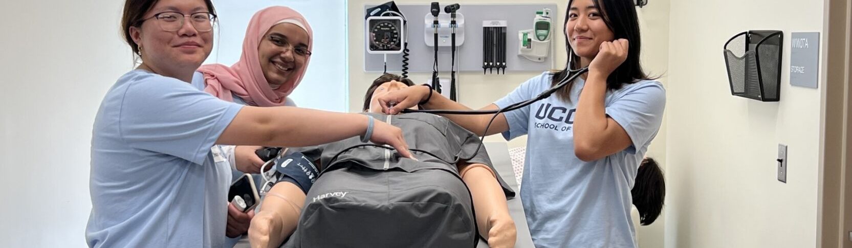 EINP4 EINP Summer 2023 in the Sim Lab - three female students taking pulse of manikin with stethoscope